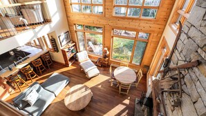 Un loft espacioso con techo alto, ventanas grandes, zona de comedor y un rincón de descanso acogedor.