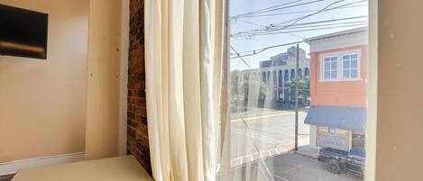 A room with a large window, a brick wall, and a flat-screen TV mounted on the wall.