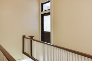 Una escalera con barandal de madera y paredes color beige.