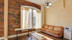 Una sala de estar con pared de ladrillo, un sofá, una mesa, una lámpara y un microondas.