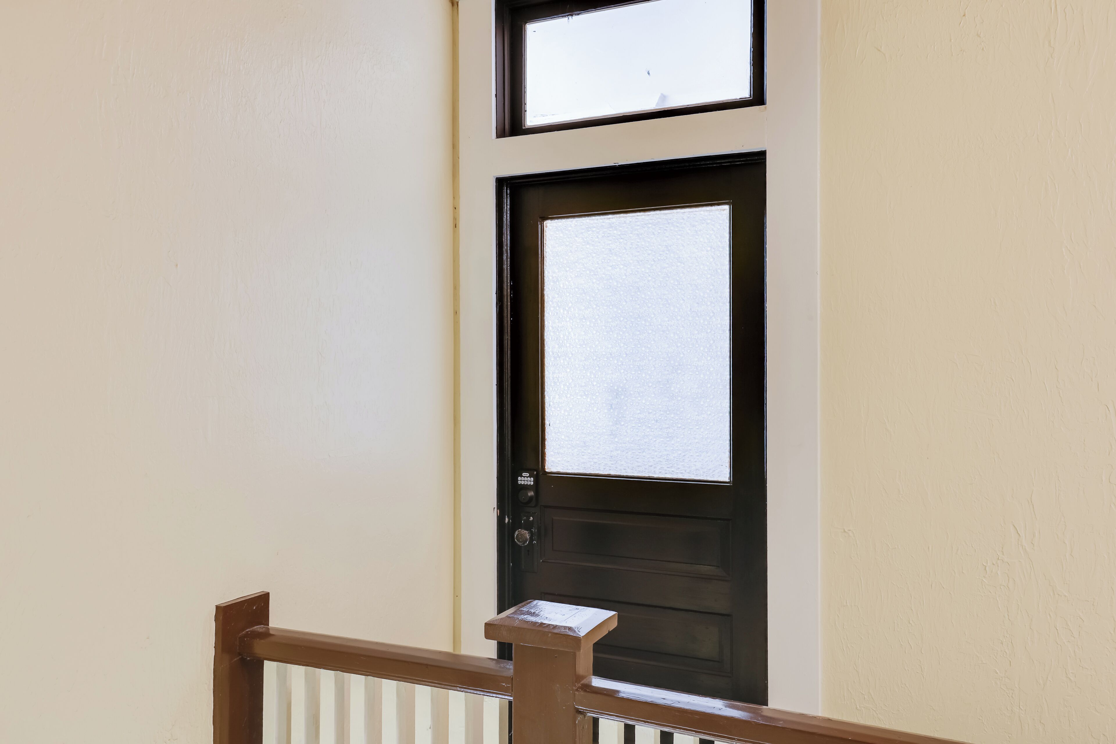 Une porte dotée d’un panneau en verre dépoli, d’un clavier pour ouvrir la porte et d’une petite boîte aux lettres située sur le côté droit.