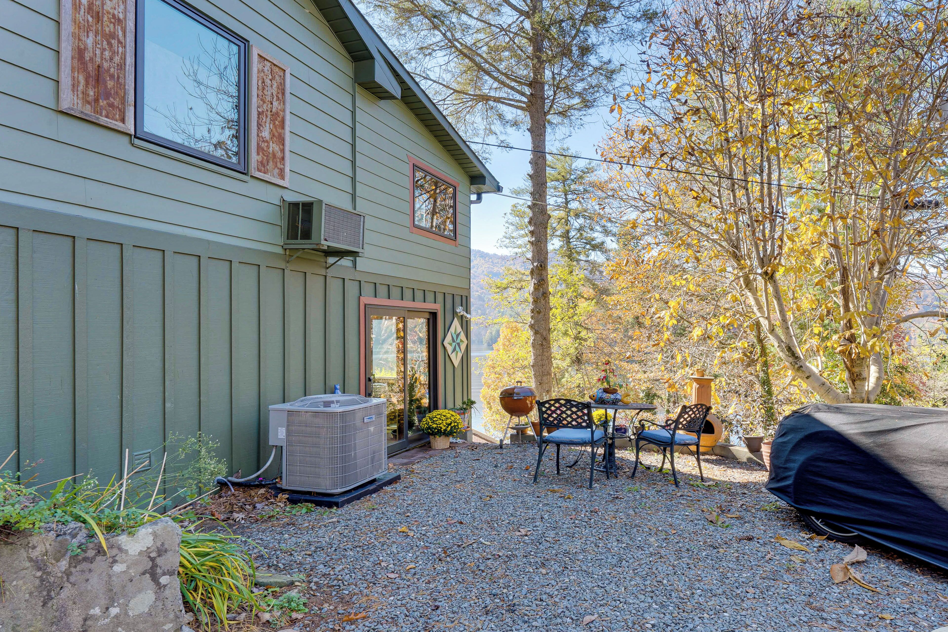A house with a gravel patio, a covered grill, and a tent.