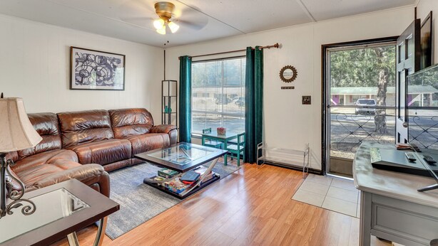 A living room with a leather sofa, a glass coffee table, a desk, and a view through a glass door. - Paddle, Hike & More: Quiet Home in High Springs! (High Springs)