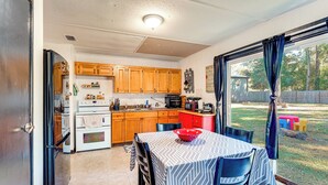 A kitchen with wooden cabinets, a refrigerator, a stove, and a dining table with chairs. - Paddle, Hike & More: Quiet Home in High Springs! (High Springs)