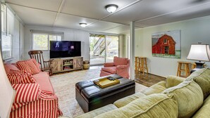 A living room with striped sofas, a television, and a painting of a barn. - Dock + Views: Family Retreat on Lake Hartwell! (Townville)