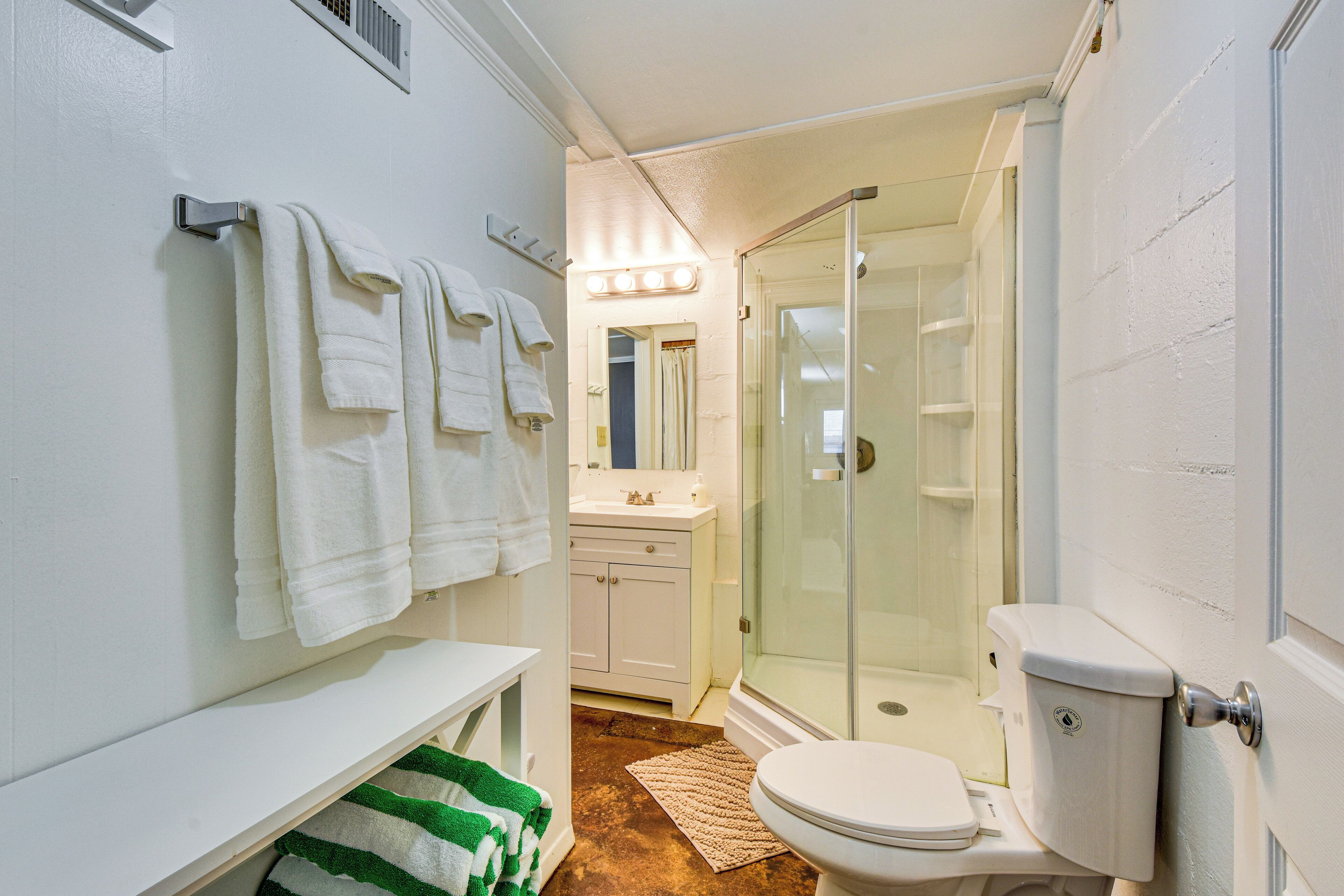 A bathroom with a toilet, a sink, a mirror, and a shower.