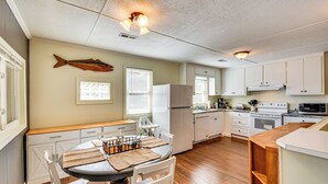 A kitchen with white cabinets, a wooden countertop, and a dining area with a table and chairs. - Dock + Views: Family Retreat on Lake Hartwell! (Townville)