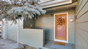 Une maison avec une porte d’entrée en bois, une couronne décorative et un paillasson.