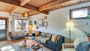 Un salon chaleureux avec un plafond en bois, un canapé, une table basse et une lampe.
