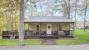 A rustic cabin with a porch, wooden deck, and a front door with a wreath. - Walk to Marina & Beach: Charming Home in Hardin (Hardin)