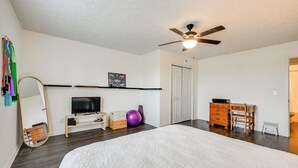 A bedroom with a bed, a ceiling fan, a TV, a dresser, a mirror, a shelf with a picture, and a door. - 6 Mi to Mammoth Cave! Mtn-view Home w/ Fire Pit (Cave City)