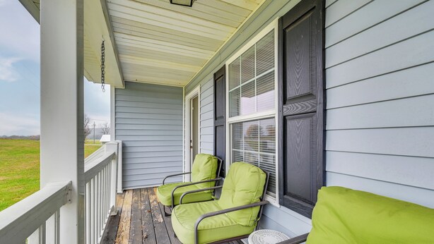 A porch with two green chairs and a small table, a white railing, and a window with blinds. - 6 Mi to Mammoth Cave! Mtn-view Home w/ Fire Pit (Cave City)