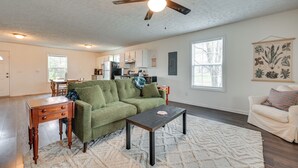 A spacious living room with a green sofa, a wooden coffee table, and a ceiling fan. - 6 Mi to Mammoth Cave! Mtn-view Home w/ Fire Pit (Cave City)