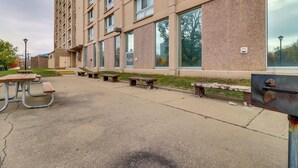 Ein Mehrstöckgebäude mit großen Fenstern und einem Parkplatz mit Picknicktischen.