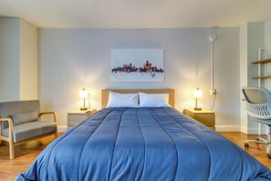 A hotel room with a large bed, two bedside tables with lamps, a chair, and a cityscape artwork on the wall. - Near Stadiums, Parks & Hospitals: Detroit Studio (Detroit)