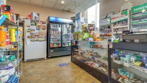 Ein Ladeninneres mit Regalen voller verschiedener Produkte, einer Kühlvitrine und einer Kasse.