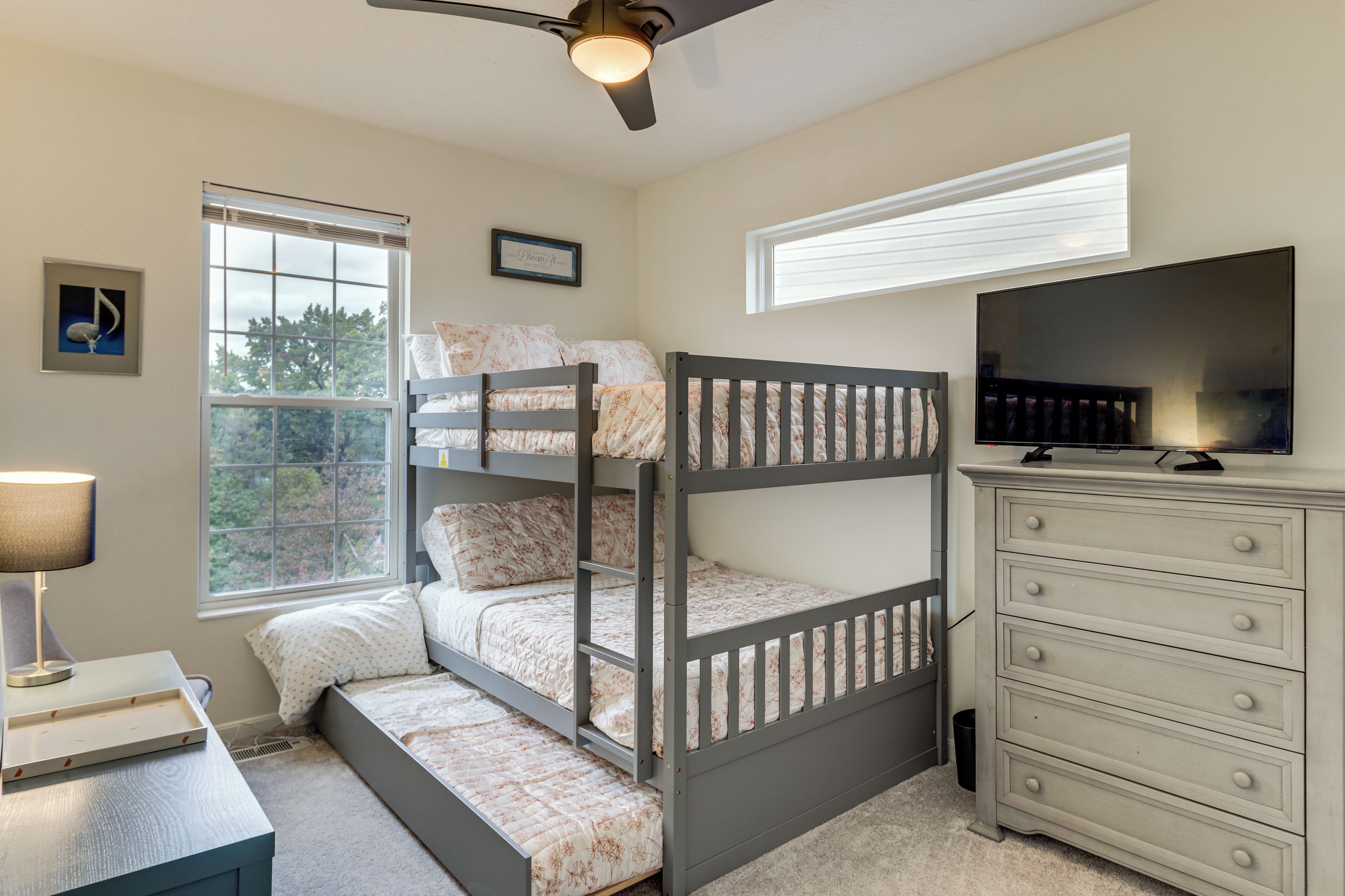 A bunk bed with a TV and dresser in a bedroom.