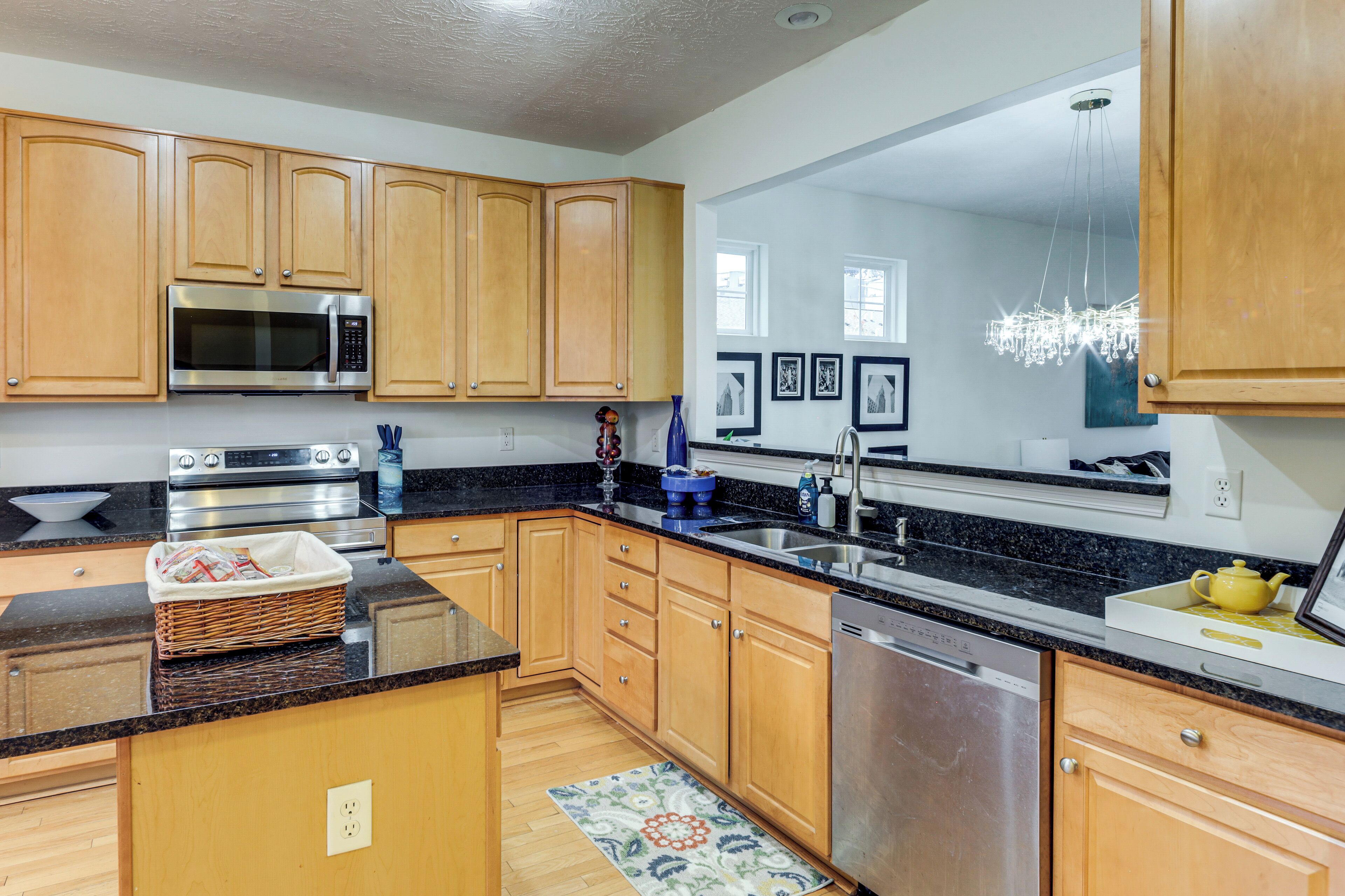 A modern kitchen with wooden cabinets, stainless steel appliances, and a black granite countertop.