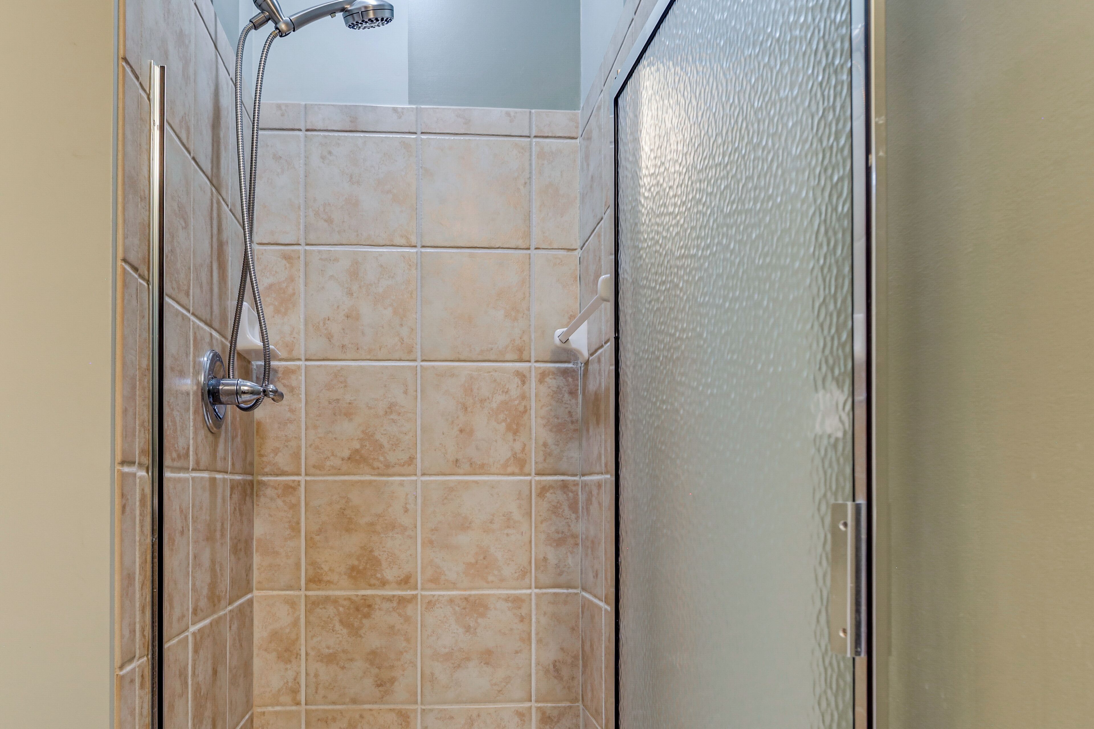 A shower with beige tiles and a glass door.