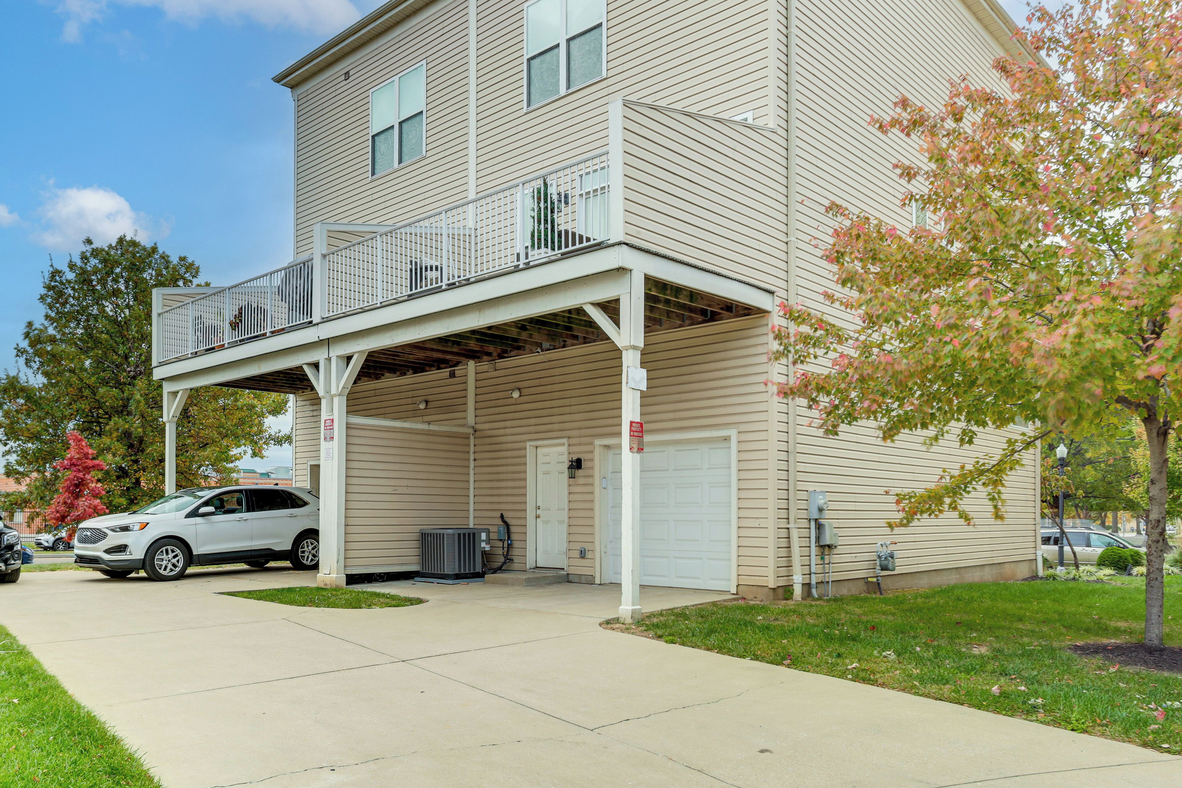 A two-story building with a covered parking area, a garage, and a small outdoor deck.