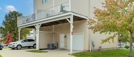 A two-story building with a covered parking area, a garage, and a small outdoor deck.
