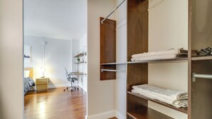 Un dormitorio con suelo de madera, una cama, una mesita de noche y un armario con estantes.