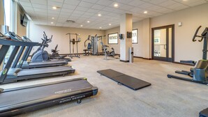 Un gimnasio con cintas de correr, máquinas de pesas y un espejo grande.