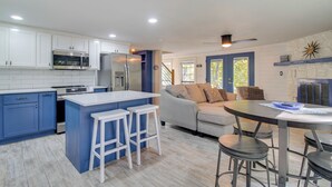 A modern kitchen with white and blue cabinets, stainless steel appliances, and a central island with stools. - Game Room, Dock & Hot Tub: Grand Lake Getaway (Afton)