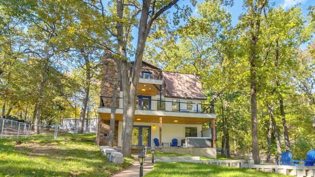 A two-story house with a stone facade, a balcony, and a covered porch. - Game Room, Dock & Hot Tub: Grand Lake Getaway (Afton)