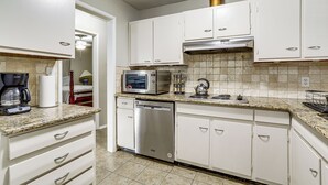 A kitchen with white cabinets, a microwave, a coffee maker, and a dishwasher.