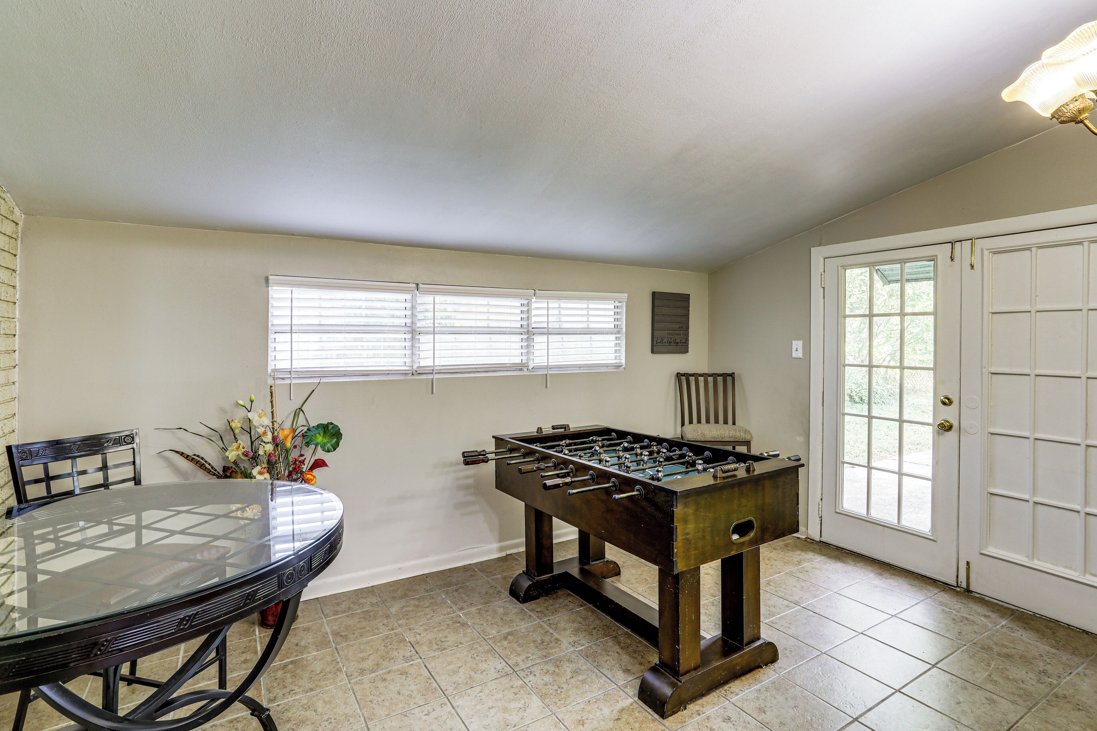 A room with a foosball table, a glass-top dining table, and a door with a window.