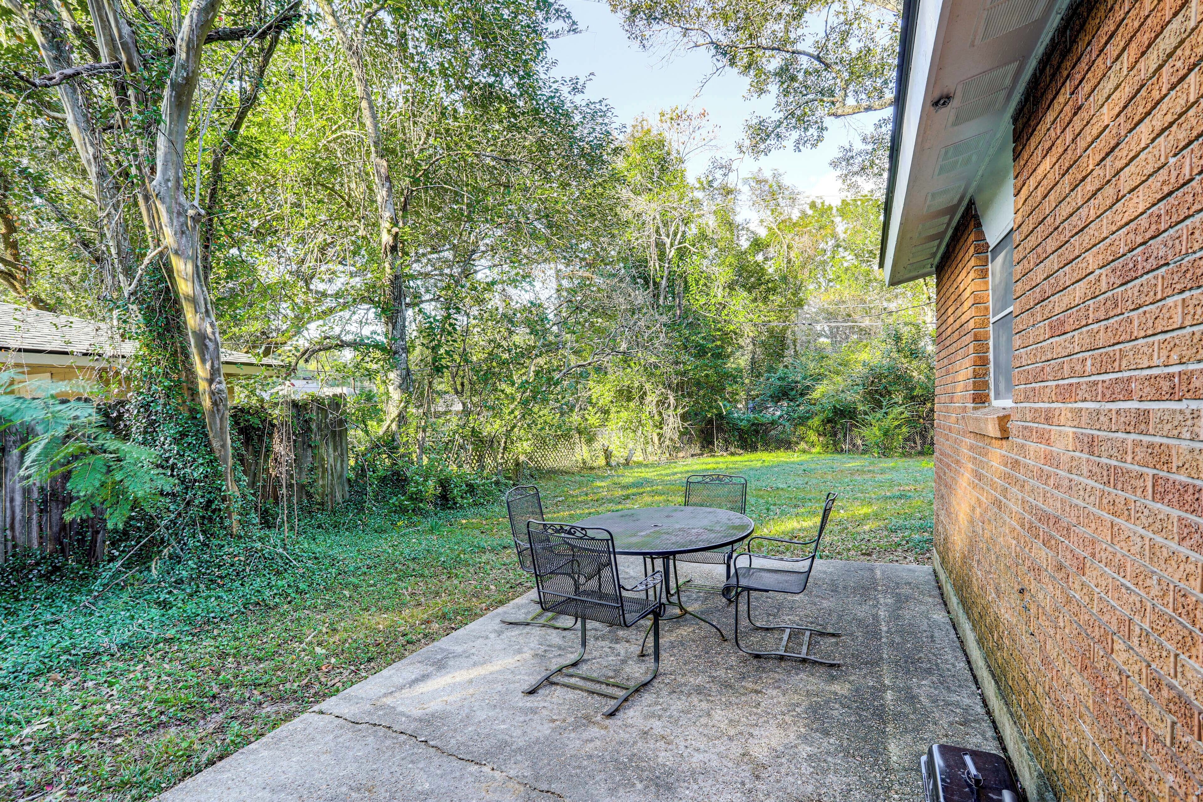 A patio with a round table and chairs, surrounded by a brick wall and greenery.