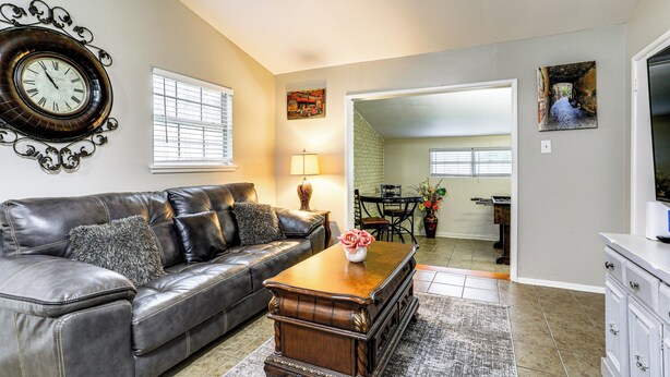 A living room with a leather sofa, a wooden coffee table, a clock, and a painting on the wall.