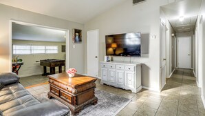 A spacious living room with a leather sofa, a wooden coffee table, a television, and a white cabinet.