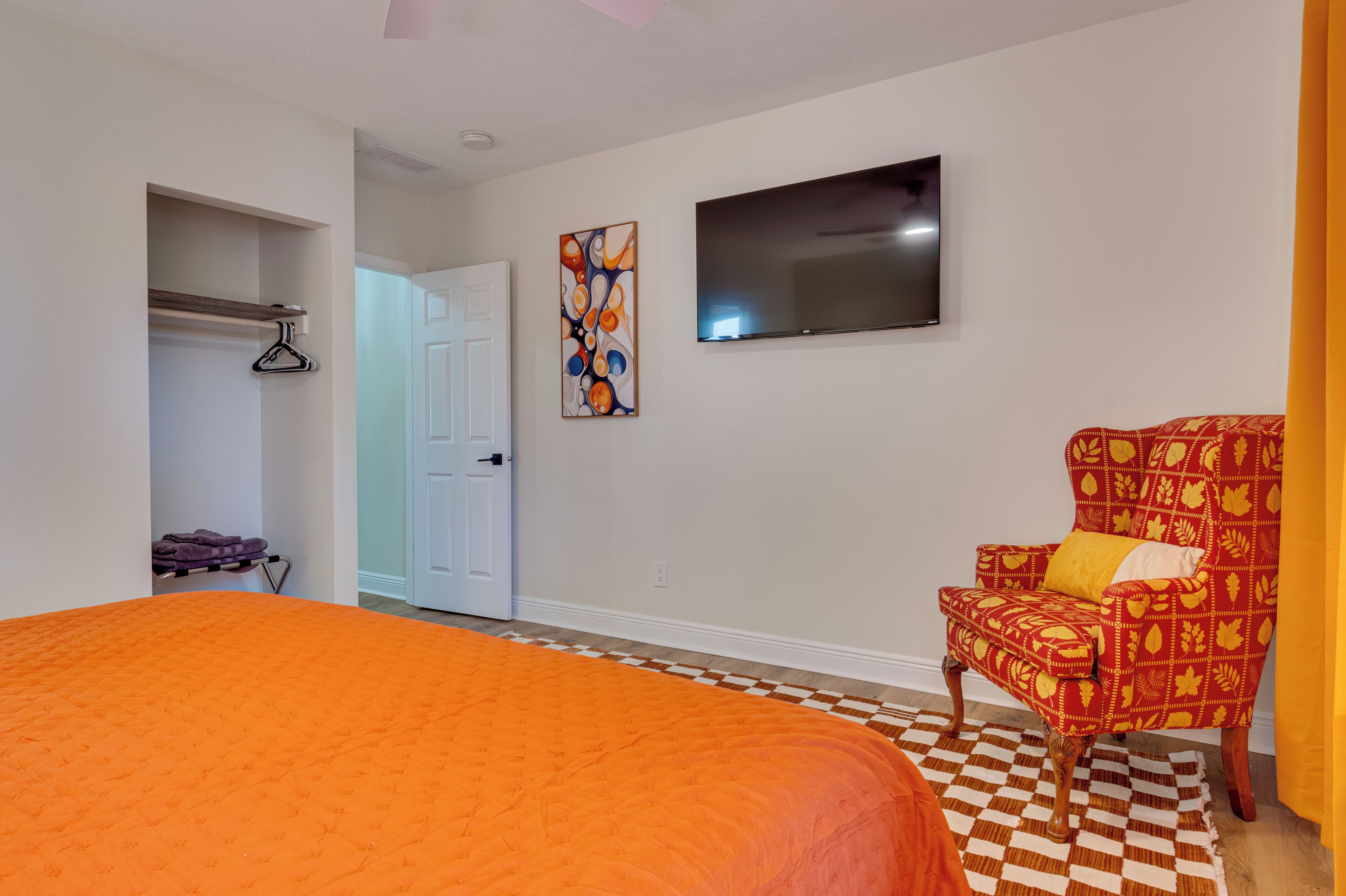 A bedroom with a large bed, a chair, a TV, and a closet.