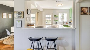 A kitchen with a white countertop, two black bar stools, and a view into the dining area. - 2 Blocks to At&t Stadium: Sports Fan Headquarters! (Arlington)