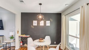 A modern dining area with a round table, white chairs, a hanging light fixture, and framed inspirational quotes on the wall. - 2 Blocks to At&t Stadium: Sports Fan Headquarters! (Arlington)