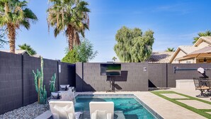 A swimming pool with two lounge chairs, a dark brick wall, and a patio area with a table and chairs. - 2 Mi to Surprise Stadium! Snowbird Haven w/ Pool (Surprise)