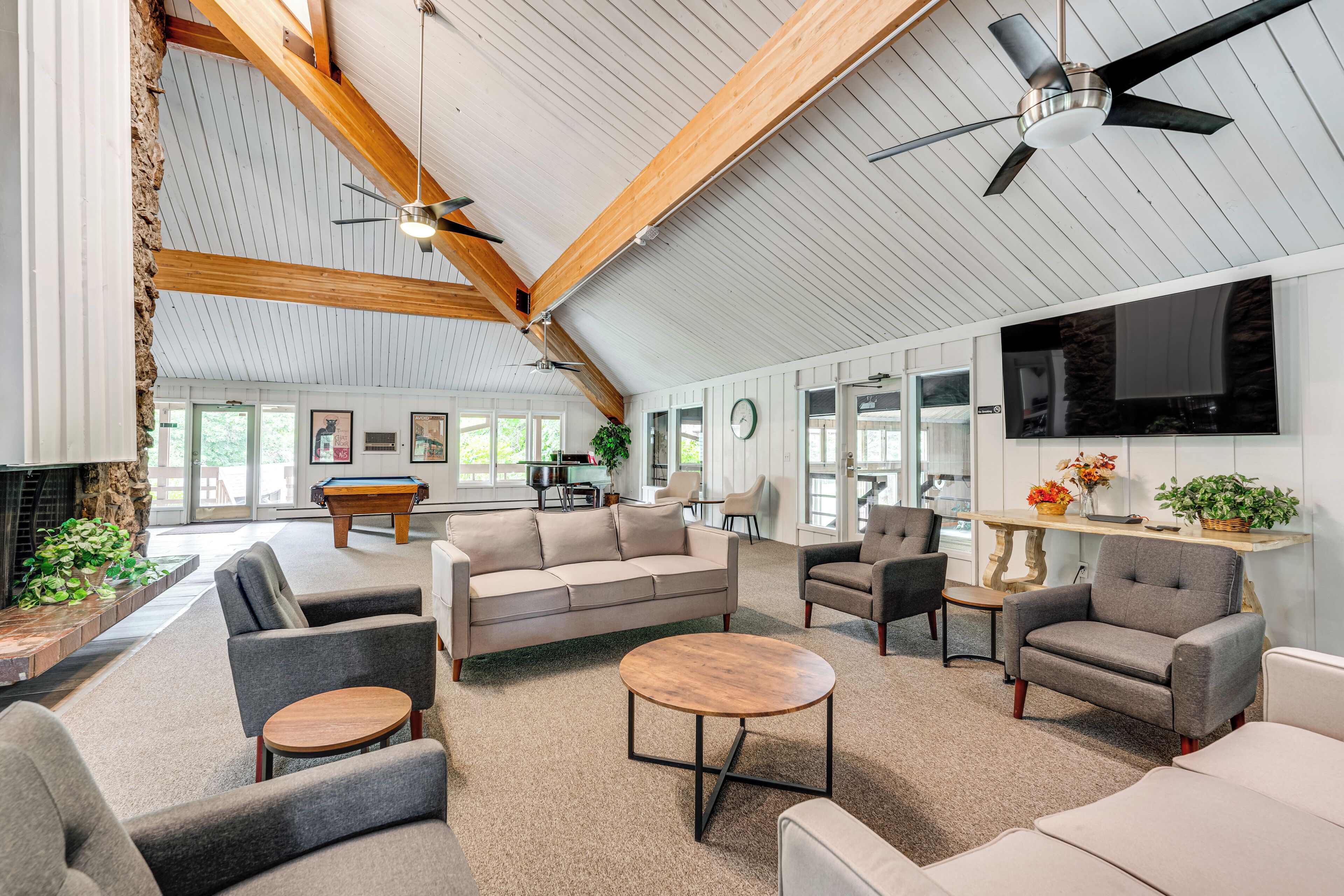 A spacious living area with a pool table, comfortable seating, a fireplace, and a large TV screen.