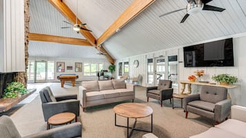 A spacious living area with a pool table, comfortable seating, a fireplace, and a large TV screen.