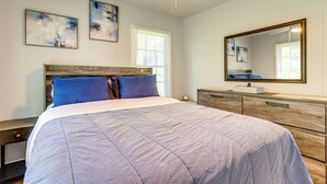 Een slaapkamer met een bed, een dressoir, een plafondventilator en twee wanddecoraties.