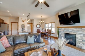 A spacious living room with a leather sofa, a fireplace, and a flat-screen TV mounted above it. - < 5 Mi to Winter Park: Family Base Camp w/ Hot Tub (Fraser)