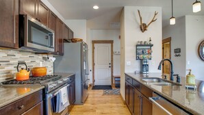 Una cocina con armarios de madera, un refrigerador de acero inoxidable, un microondas y una estufa.