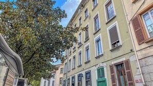 A street view with buildings, trees, and a clear sky.