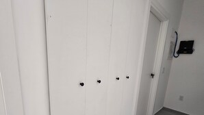Et værelse med en stor, hvid garderobe, flisegulv og en dør til et andet rum.
