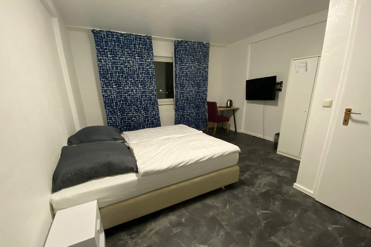 Una camera da letto con un letto, una scrivania, una sedia e una televisione.