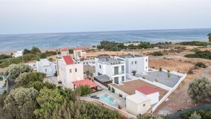 Un complex residencial modern amb diversos edificis, una piscina i vista al mar.