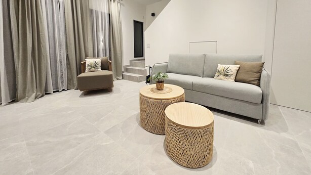 A modern living room with a grey sofa, a beige armchair, and two round wicker coffee tables. - Soleil & Sage Haven,2BR Townhouse in Cupecoy (Cupercoy)