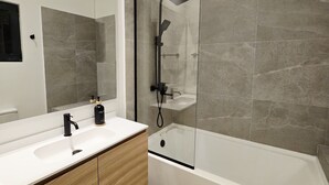 A modern bathroom with a large mirror, a white sink, a wooden vanity, and a glass-enclosed shower area. - Soleil & Sage Haven,2BR Townhouse in Cupecoy (Cupercoy)