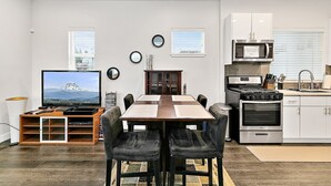 A modern kitchen with a dining area, featuring a TV, wooden table, and chairs. - 2 Bed MIL unit with Lake Washington views (Seattle)